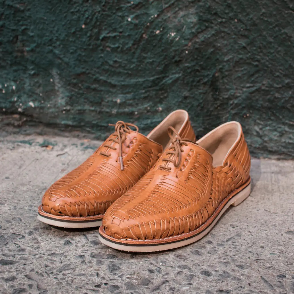 Les Derbies Autentico Came sont posées sur un sol goudronné, dos à un mur en crépit vert foncé.