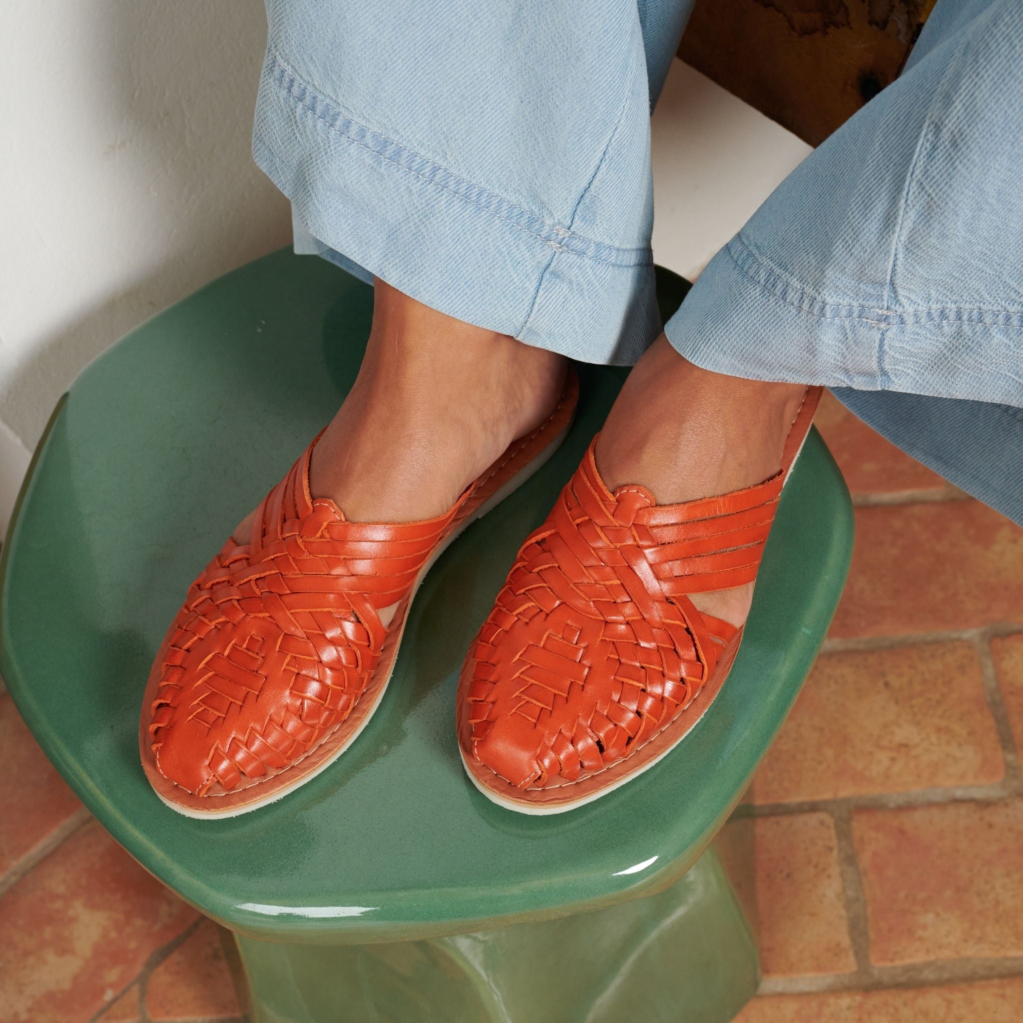 Emilia Orange - Mapache - Laura porte des Mules Emilia Orange, mettant en avant leur design simple et leur teinte vibrante.