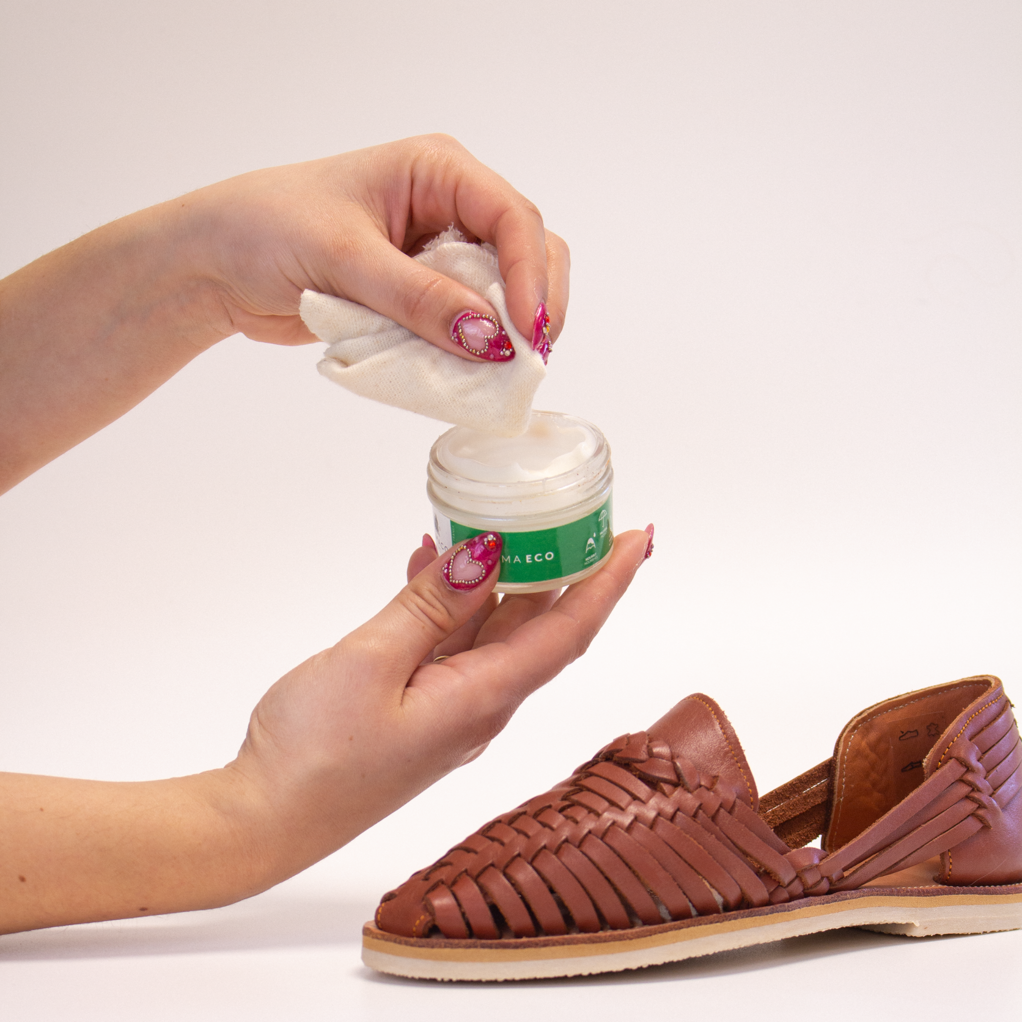 Une main prélève délicatement un peu de pommadier FAMA ECO de FAMACO avec le chiffon doux fourni, prête à nourrir une huarache Alegre Camel de Mapache.