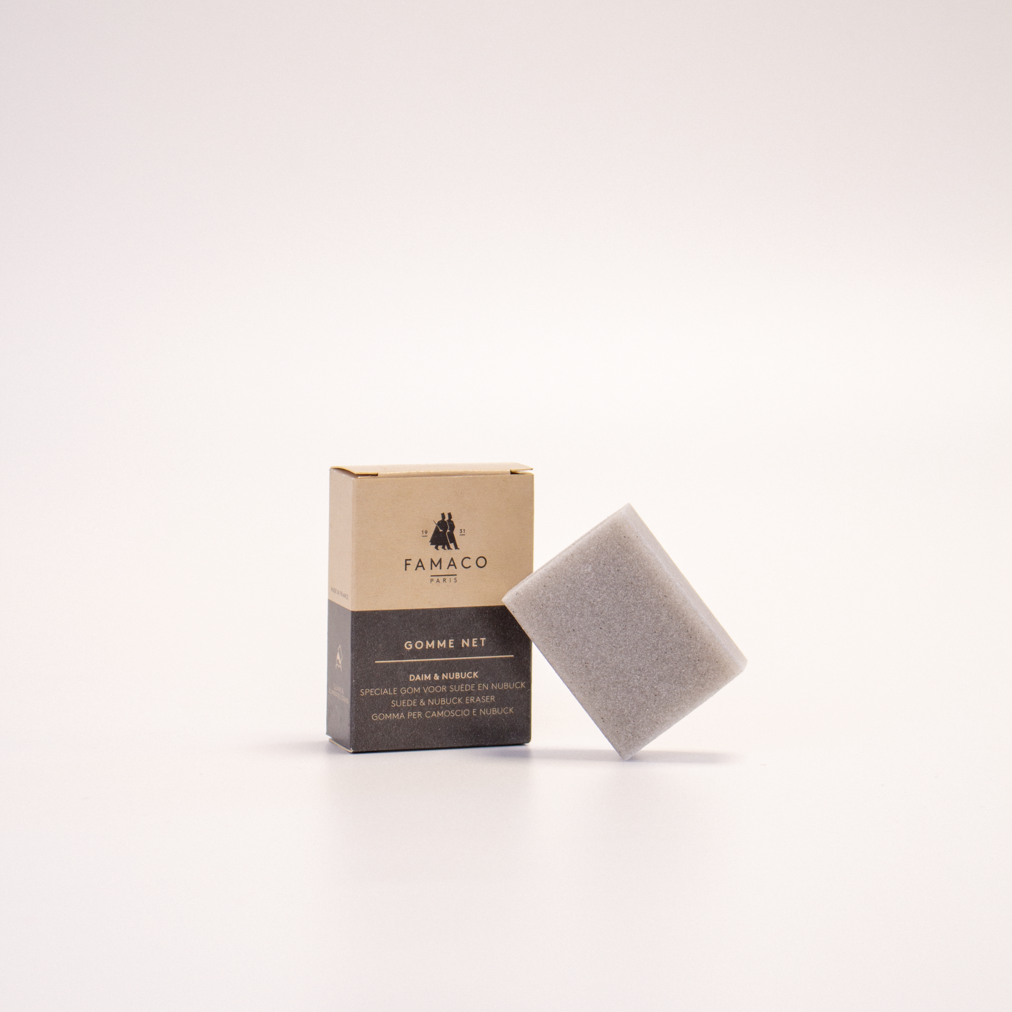 La GOMME NET de FAMACO est posée sur un fond blanc, inclinée à côté de son emballage en carton.