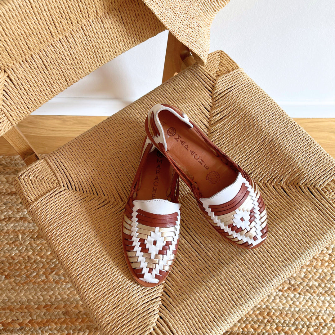Les Huaraches Ibarra Tabac Champagne sont posées sur une chaise en ficelle tressée dans un décor beige.
