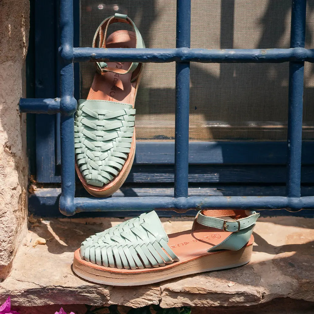 Les Sandales Loma Menthes sont exposées devant et derrière les barreaux bleus d'une fenêtre dans la rue.