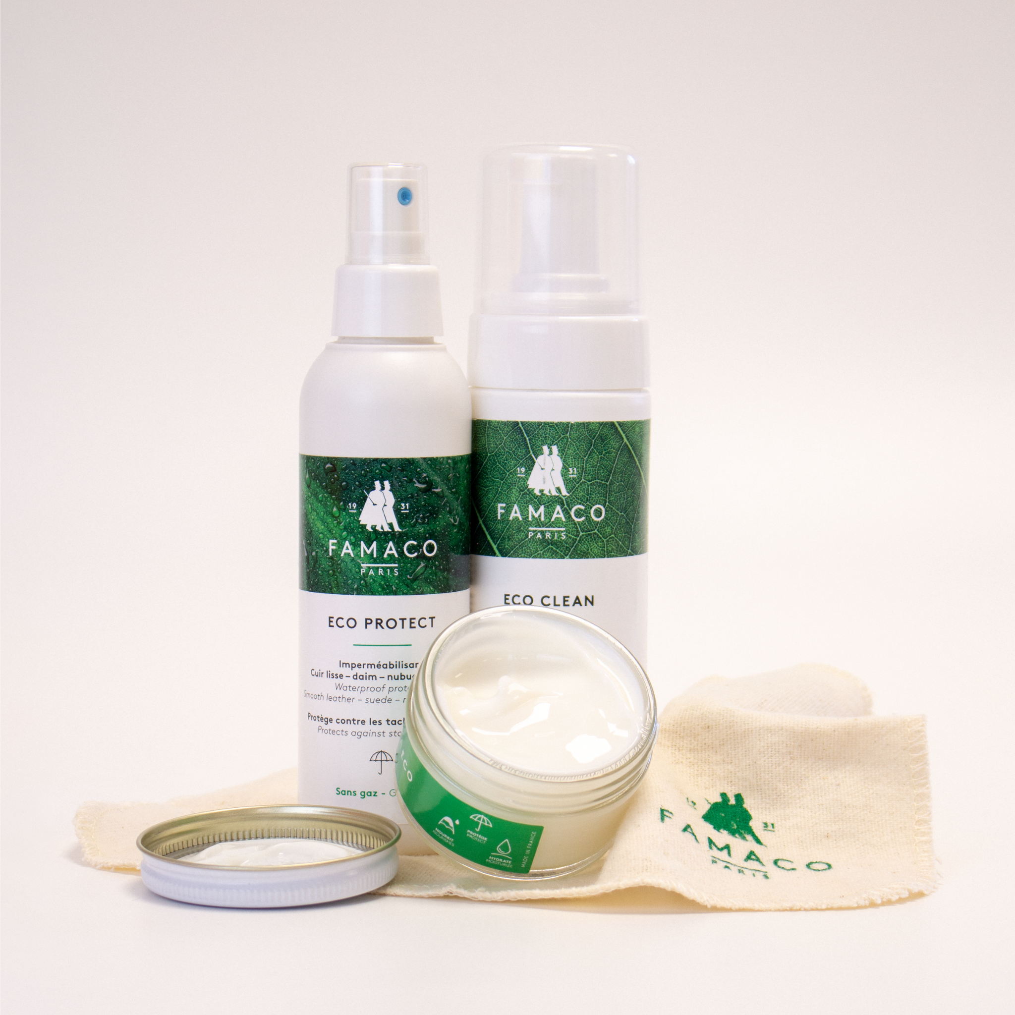Le PACK ECO de FAMACO présente le pommadier FAMA ECO ouvert devant le spray imperméabilisant ECO PROTECT et la mousse nettoyante ECO CLEAN, superposés au chiffon doux fourni, sur un fond blanc.