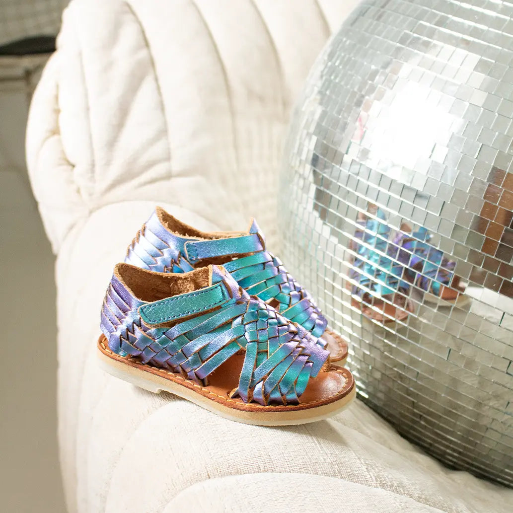 Les Sandales Sandalita Blue Mermai sont posées sur le coin d'un canapé et reflètent dans une boule à facette.