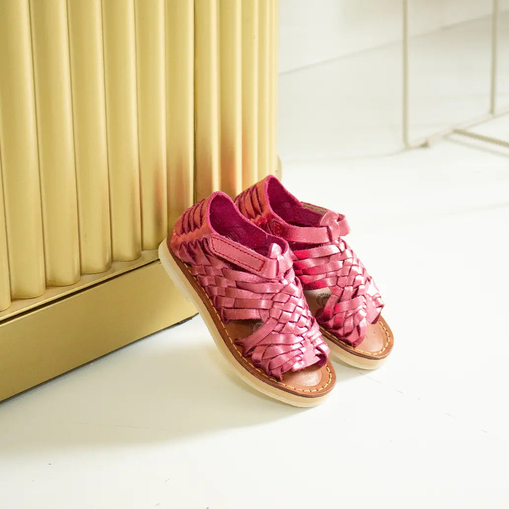 Les Sandales Sandalita Rose Flashy sont appuyées contre un meuble comptoir doré.