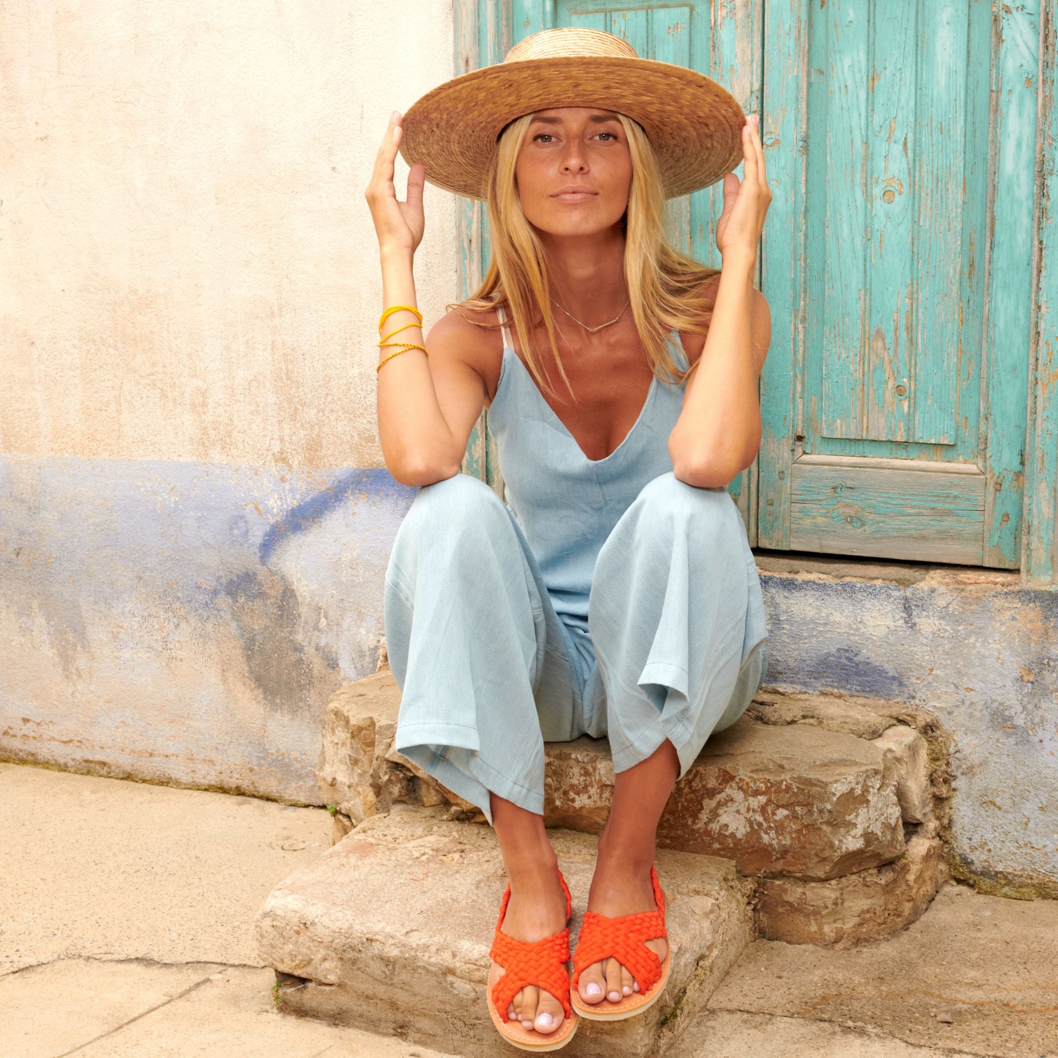 Laura, assise, porte les sandales Zula Orange tressées en nylon orange à ses pieds.