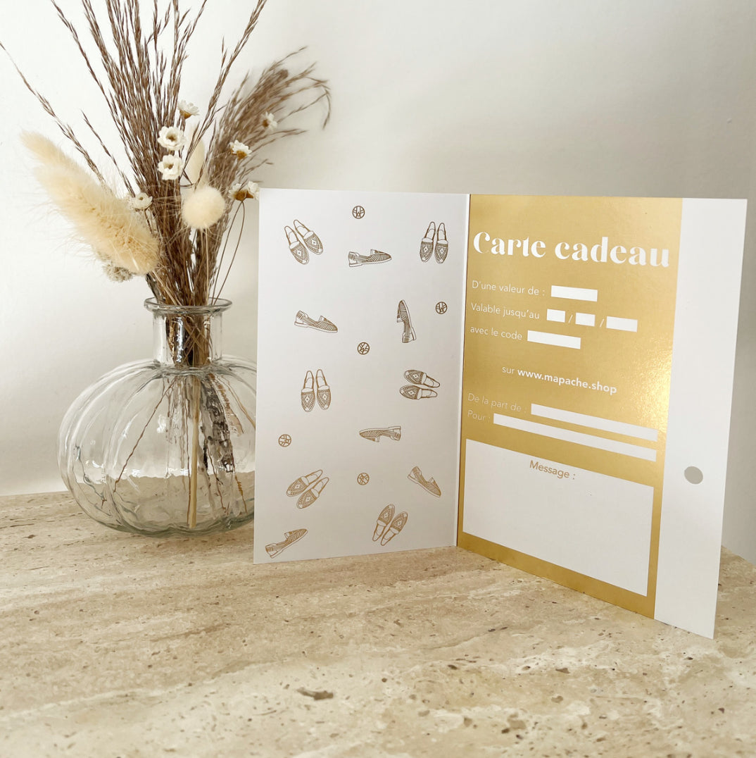 Une carte ouverte montrant les champs à remplir sur une commode en marbre à côté d'un pot de fleurs transparent.