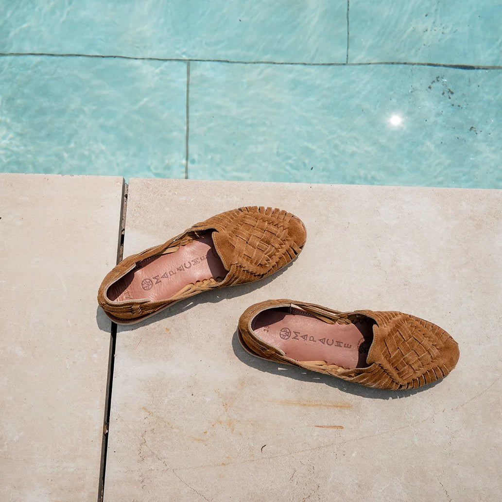 Les Huaraches Rosalia Suede Camel sont posées sur des dalles au bord d'une piscine.