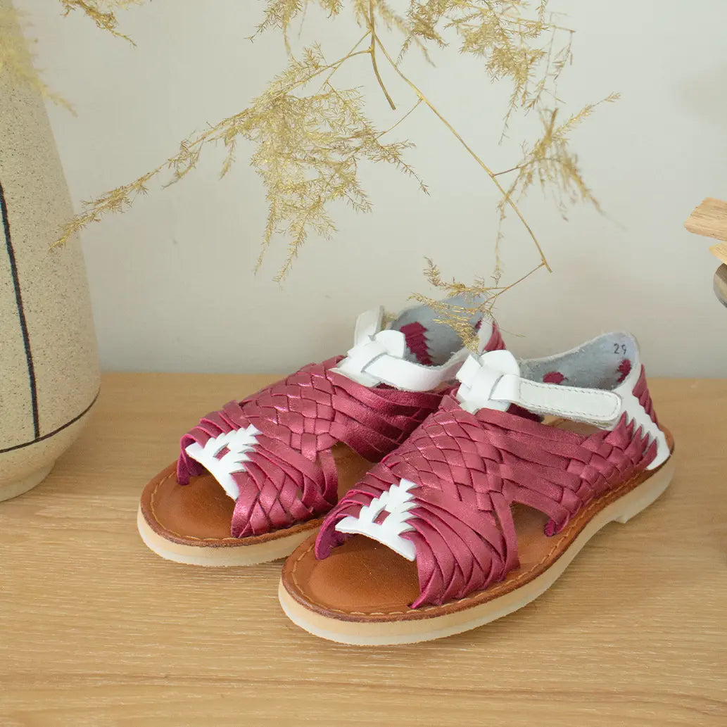 Les Sandales Sandalita Rose Flashy Blanc sont posées sur une étagère en bois clair à côté de fleurs séchées.